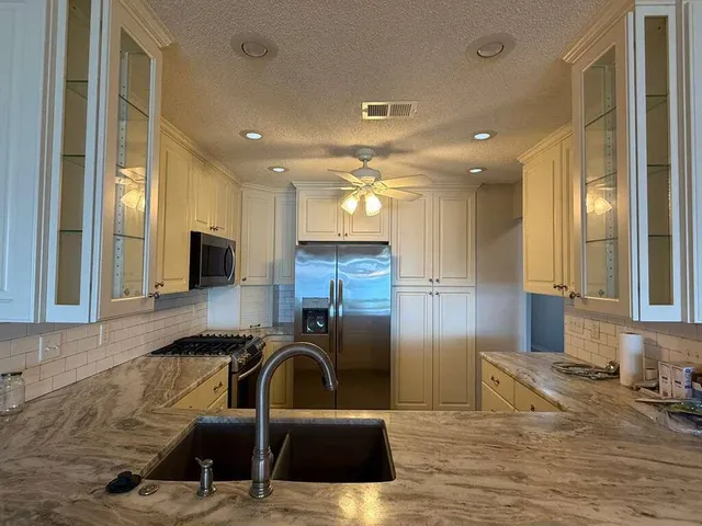 a kitchen with stainless steel appliances granite countertop a sink a stove and a refrigerator