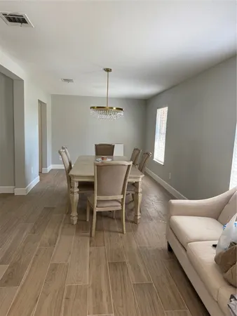 a dining room with furniture a chandelier and wooden floor