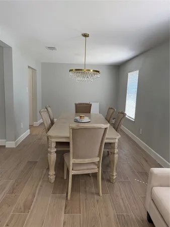 a dining room with furniture a chandelier and wooden floor