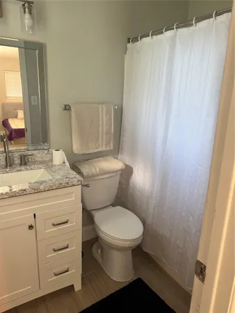 a bathroom with a granite countertop toilet sink and mirror