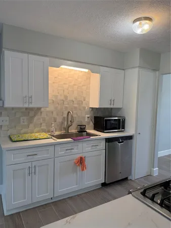 a kitchen with granite countertop white cabinets and white appliances