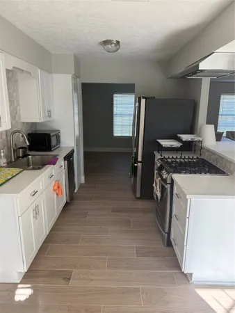a kitchen with stainless steel appliances a stove top oven a sink dishwasher and a refrigerator