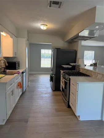 a kitchen with a stove top oven a sink a counter space and cabinets