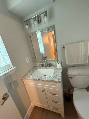 a bathroom with a granite countertop sink toilet and mirror