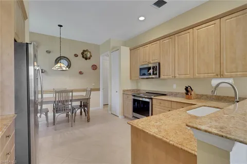 a kitchen with a refrigerator a stove a sink and a dining table with wooden floor