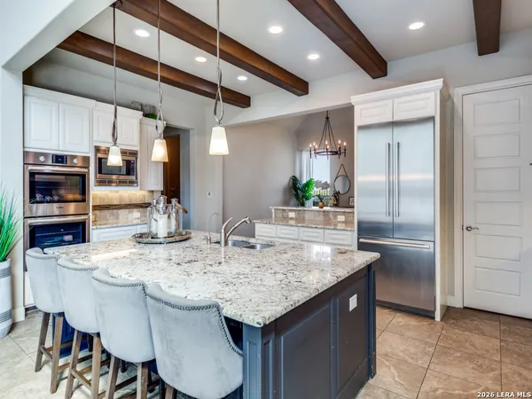 a kitchen with stainless steel appliances granite countertop a kitchen island a stove a refrigerator a oven and a sink