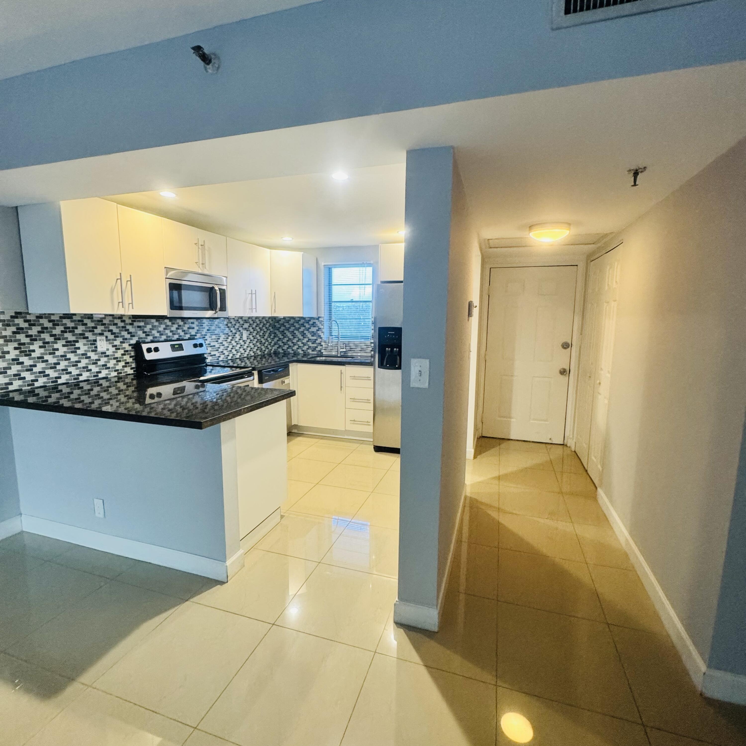 9235 Southwest 8th Street, Unit 503 Boca Raton, FL 33428 - Photo 3 of 17 a kitchen with stainless steel appliances granite countertop a sink and a stove