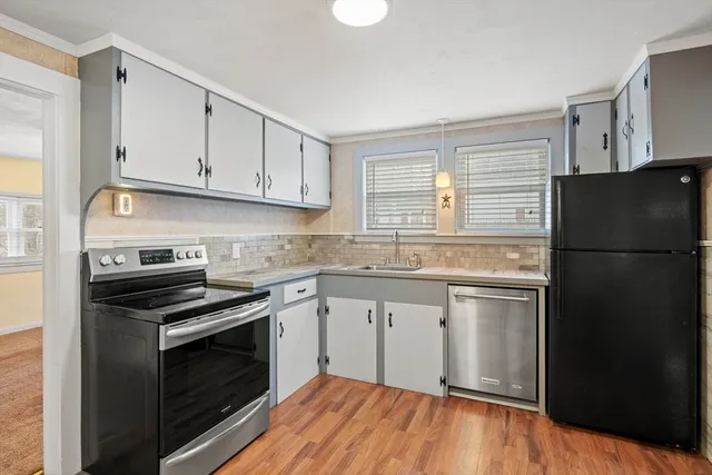 a kitchen with granite countertop white cabinets stainless steel appliances and a window