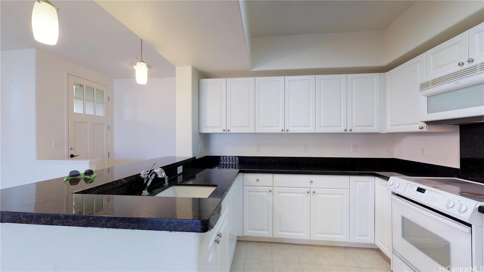 92-1033 Koio Drive, Unit M156 Kapolei, HI 96707 - Photo 11 of 20 a kitchen with granite countertop white cabinets and black appliances
