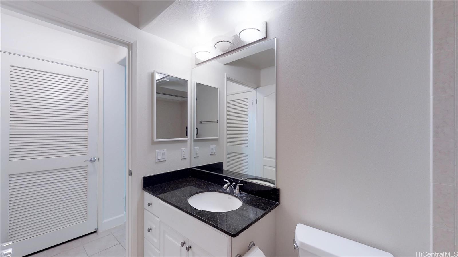 92-1033 Koio Drive, Unit M156 Kapolei, HI 96707 - Photo 5 of 20 a bathroom with a granite countertop sink and a mirror