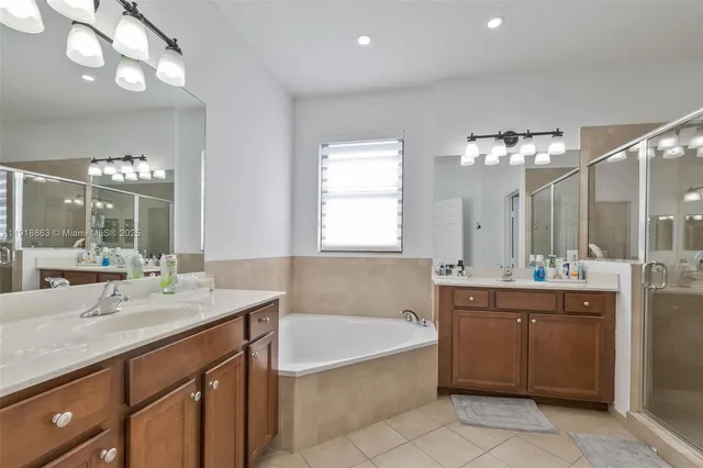 a bathroom with a bathtub a double vanity sink and mirror