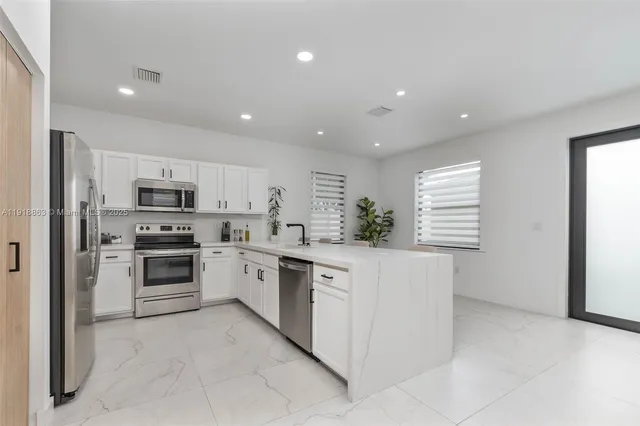 a kitchen with granite countertop white cabinets and stainless steel appliances