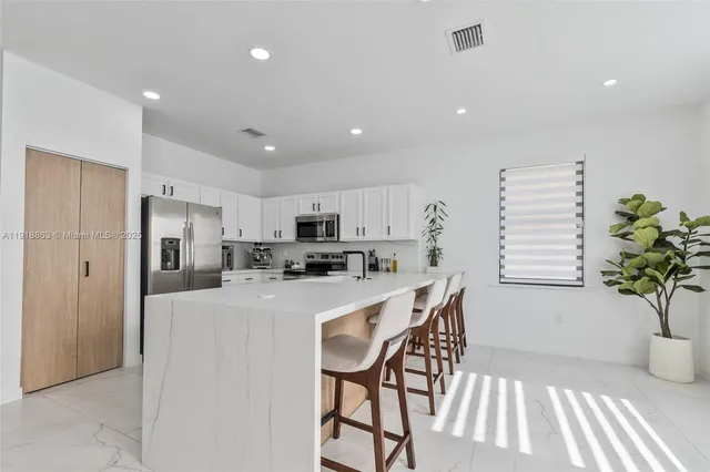 a kitchen with stainless steel appliances kitchen island granite countertop a refrigerator and a dining table