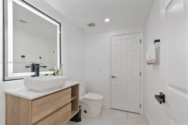a bathroom with a sink a toilet a mirror and shower