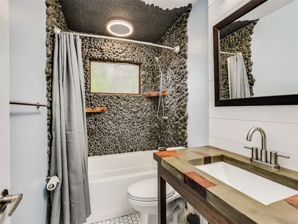 a bathroom with a sink a toilet a mirror a vanity and shower