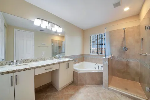 a bathroom with a granite countertop bathtub a sink and a mirror