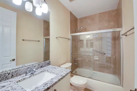 a bathroom with a granite countertop sink a toilet and shower