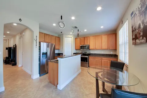 a kitchen with stainless steel appliances kitchen island granite countertop a refrigerator and a stove top oven