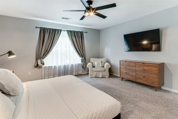 a bedroom with a bed a flat screen tv and a couch