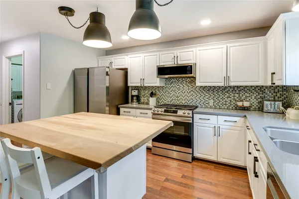 a kitchen with stainless steel appliances kitchen island granite countertop a refrigerator a sink dishwasher a stove with wooden floor