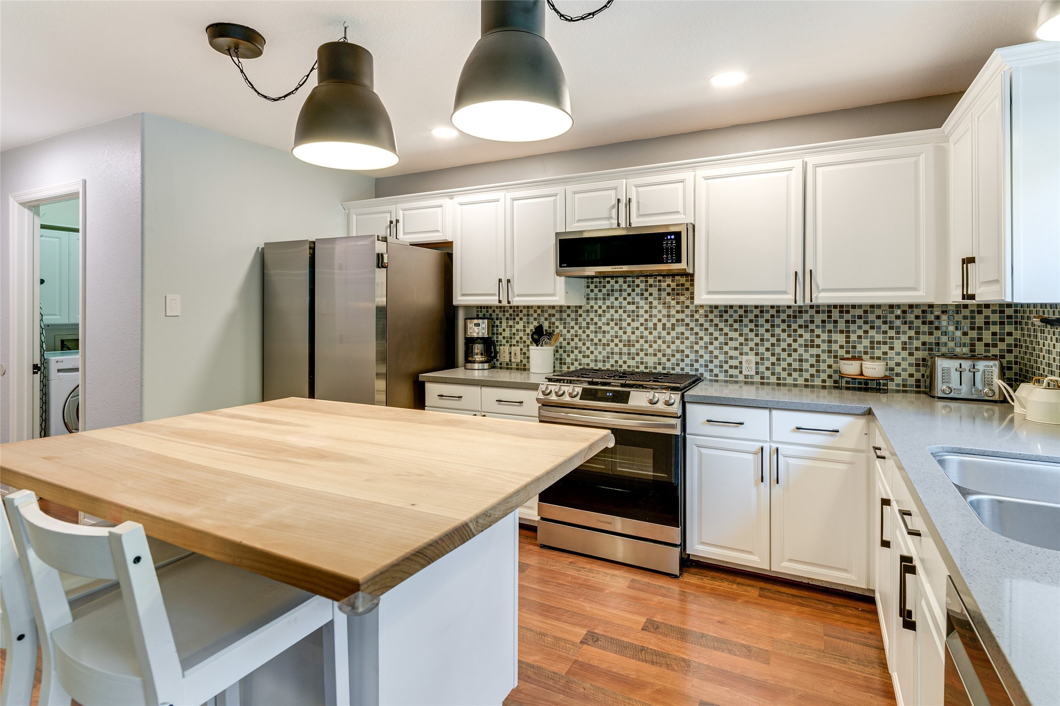 34 Steep Trail Place Conroe, TX 77385 - Photo 7 of 21 a kitchen with stainless steel appliances kitchen island granite countertop a refrigerator a sink dishwasher a stove with wooden floor