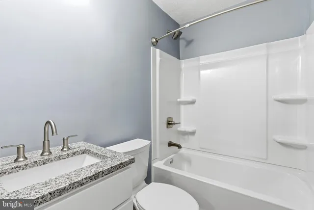 a bathroom with a granite countertop sink a toilet and shower