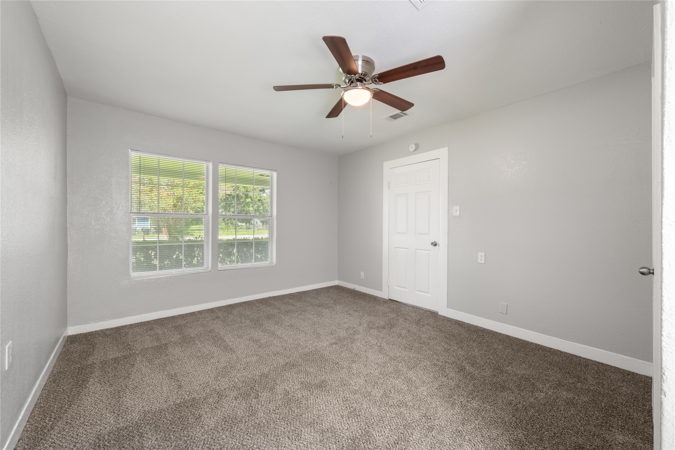 9210 Compton Street Houston, TX 77016 - Photo 8 of 50 Spacious bedroom featuring soft carpet flooring, large windows for natural light, and a ceiling fan for comfort.