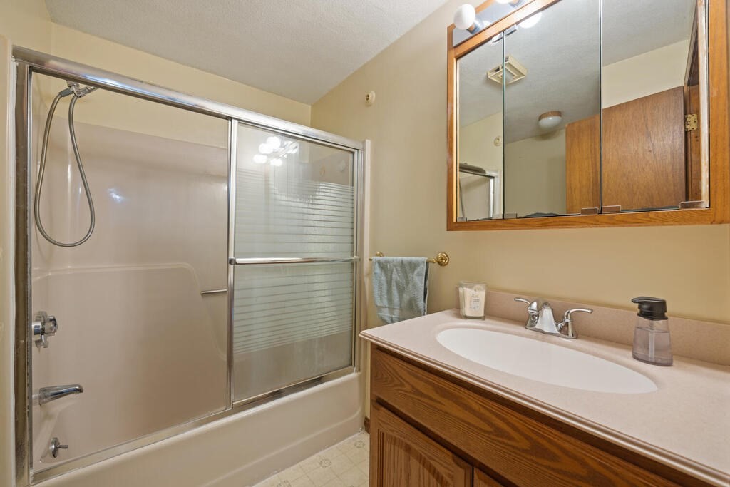 802 Lawrence Street, Unit D Lowell, MA 01852 - Photo 21 of 26 a bathroom with a granite countertop sink a shower and a mirror
