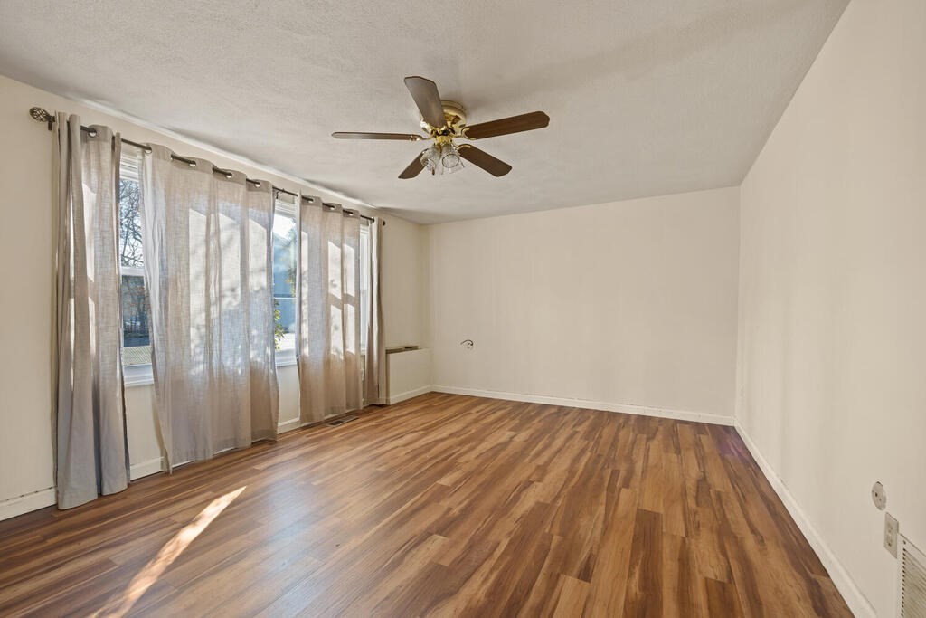 802 Lawrence Street, Unit D Lowell, MA 01852 - Photo 9 of 26 an empty room with wooden floor fan and windows