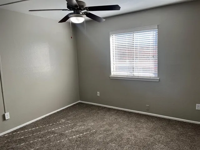 an empty room with a window and a fan