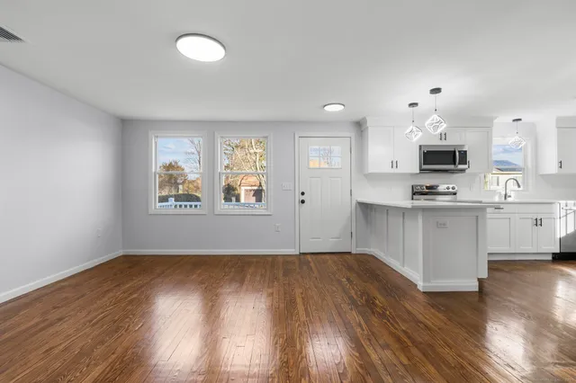 a open kitchen with white cabinets and wooden floor