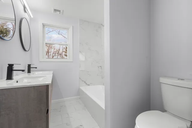 a bathroom with a toilet a sink and mirror