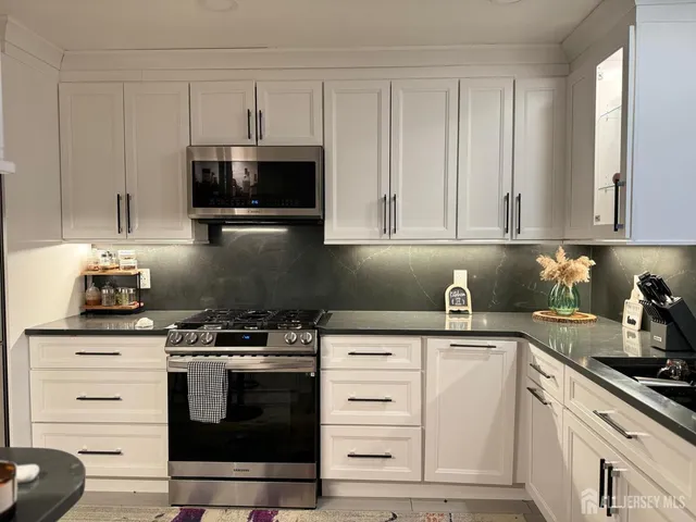 a kitchen with granite countertop white cabinets and stainless steel appliances