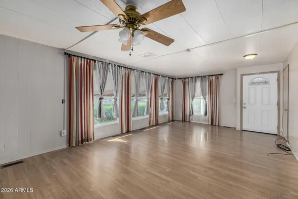 a view of an empty room with wooden floor and a window