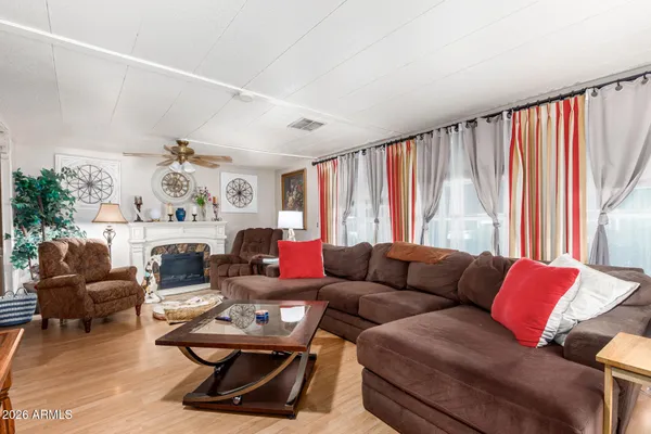 a view of an empty room with wooden floor and a ceiling fan
