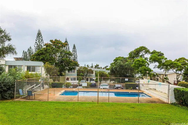 a view of a swimming pool with lawn chairs and a big yard