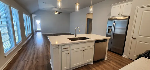 a kitchen with a sink stainless steel appliances a refrigerator and cabinets