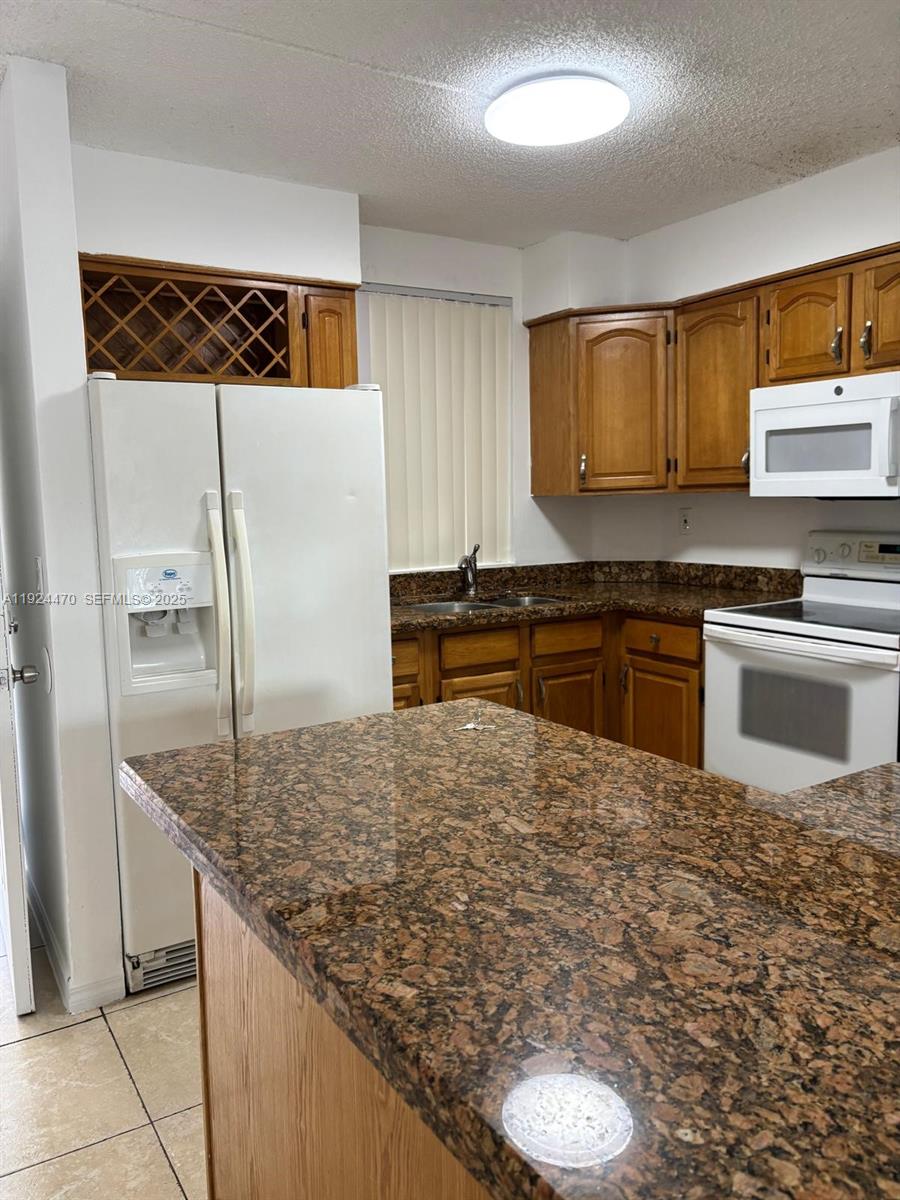 6045 Northwest 186th Street, Unit 123 Hialeah, FL 33015 - Photo 2 of 9 a kitchen with kitchen island sink and refrigerator