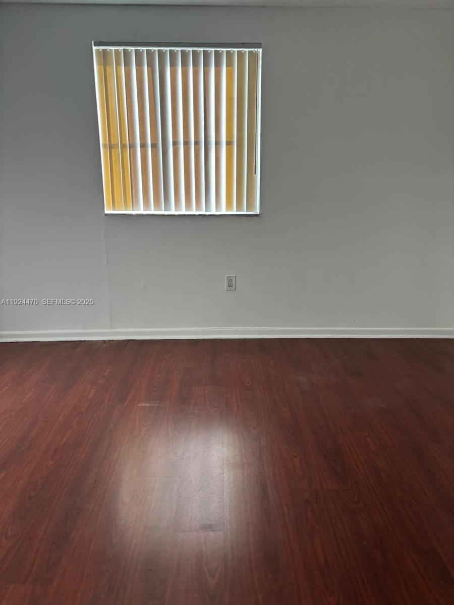 6045 Northwest 186th Street, Unit 123 Hialeah, FL 33015 - Photo 5 of 9 an empty room with wooden floor and windows