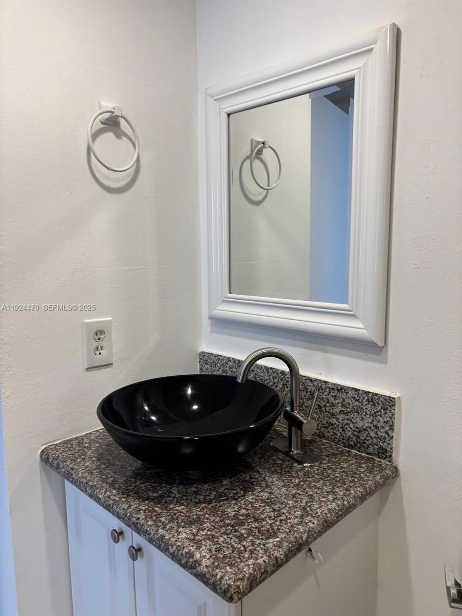 6045 Northwest 186th Street, Unit 123 Hialeah, FL 33015 - Photo 8 of 9 a bathroom with a granite countertop sink and a mirror