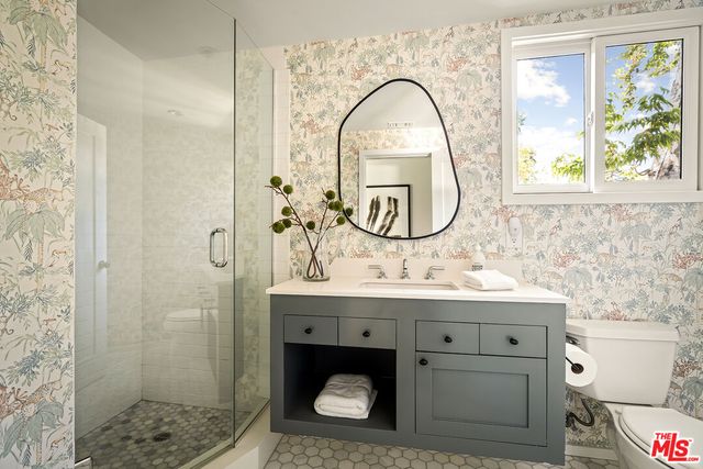 a bathroom with a sink a mirror a vanity and a shower