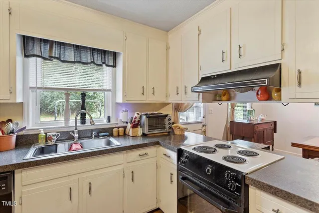 a kitchen with a stove a sink dishwasher and white cabinets with wooden floor