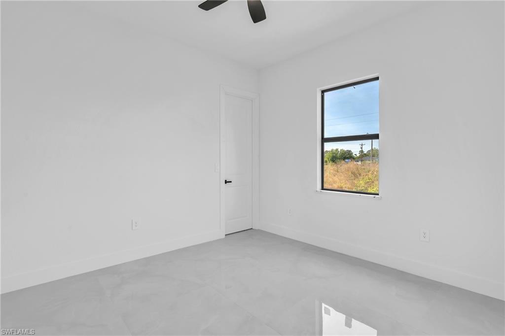 3110 23rd Street Southwest Lehigh Acres, FL 33976 - Photo 18 of 27 Empty room with finished concrete flooring and a ceiling fan