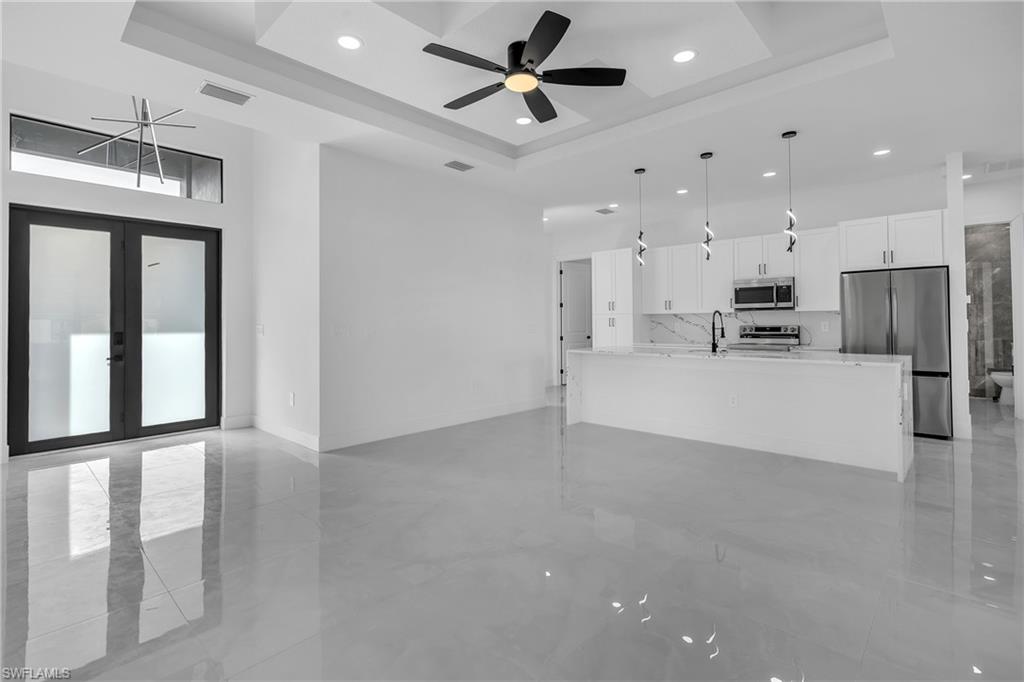 3110 23rd Street Southwest Lehigh Acres, FL 33976 - Photo 9 of 27 Unfurnished living room featuring a high tray ceiling, a ceiling fan, french doors, and recessed lighting