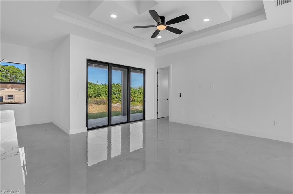 3110 23rd Street Southwest Lehigh Acres, FL 33976 - Photo 10 of 27 Spare room featuring a ceiling fan, concrete floors, plenty of natural light, a tray ceiling, and recessed lighting