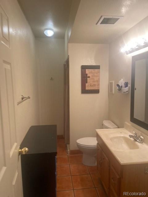 6778 Zenobia Loop, Unit 2 Westminster, CO 80030 - Photo 12 of 13 a bathroom with a granite countertop sink a toilet a mirror and a shower