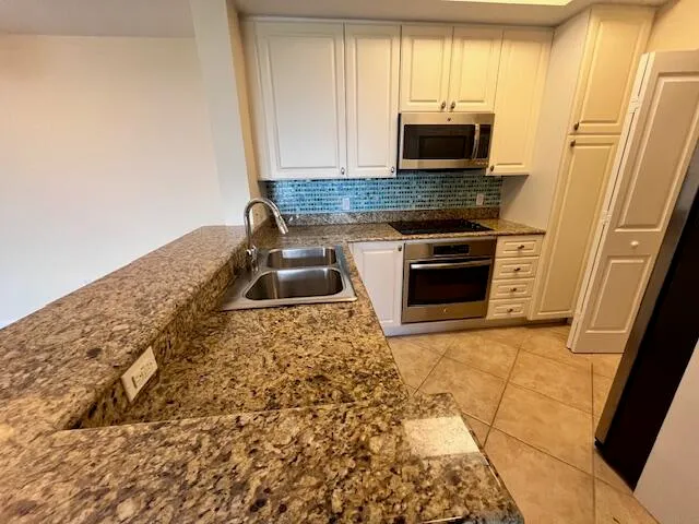 a kitchen with granite countertop a stove a microwave a sink and a counter top space