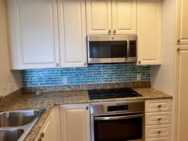 a kitchen with granite countertop a sink stove and cabinets