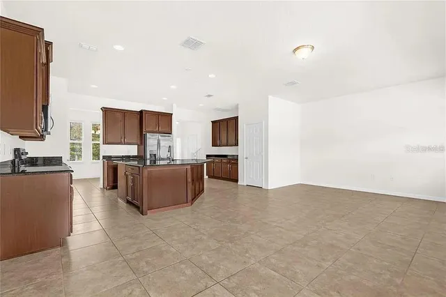 a living room with couches and kitchen view with wooden floor