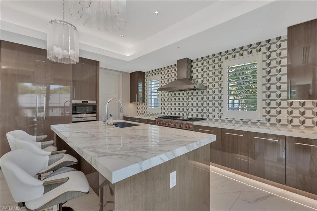 490 5th Street South, Unit 101 Naples, FL 34102 - Photo 15 of 50 a kitchen with a sink a stove and chairs